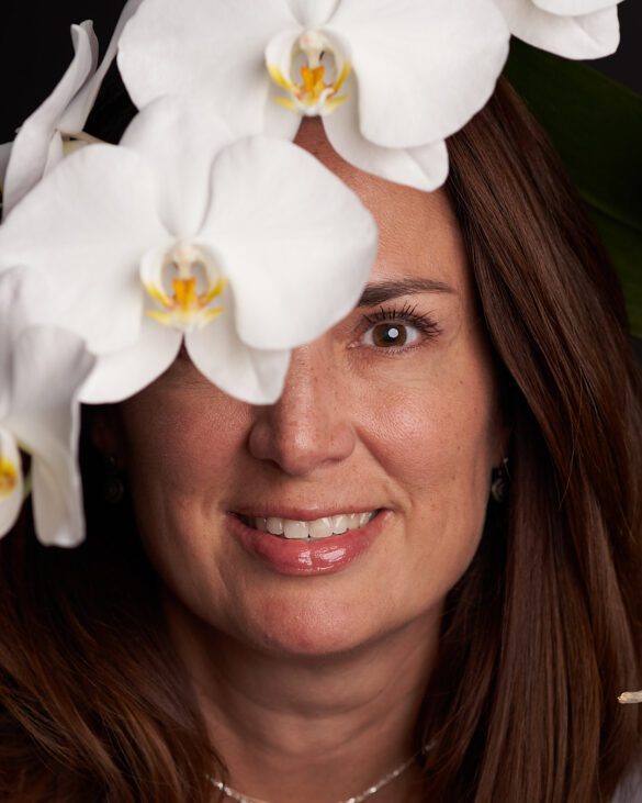 Retrato de la cara de mujer caucásica con orquídea sobre uno des su ojos